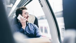Mann sitzt im Zug und telefoniert