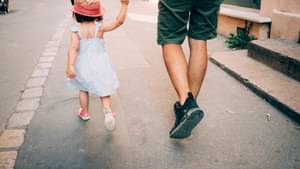 Vater läuft mit kleiner Tochter auf der Straße entlang