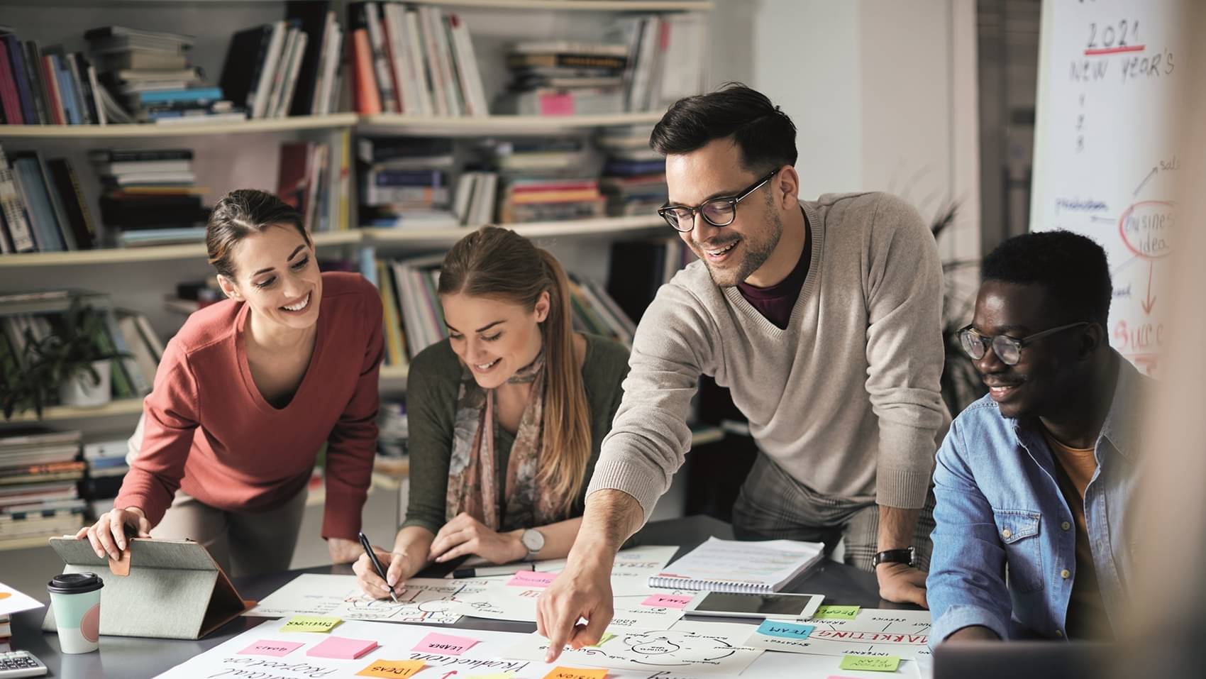 Junges Gründerteam plant gemeinsam an einem Tisch mit Notizen und Skizzen.