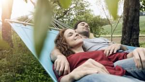 Junges paar liegt gemeinsam entspannt in einer Hängematte.