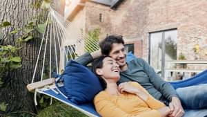 Junges Paar liegt draußen in einer Hängematte und ist glücklich.