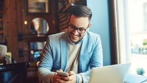 Junger Mann mit Handy in der Hand informiert sich über ETF-Sparpläne